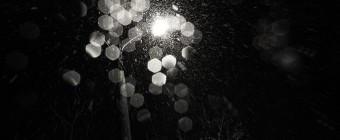 A black and white abstract photograph of a street light with falling snow. Shot with plentiful bokeh in a film noir style. Taken by Manahawkin, NJ, photographer Greg Molyneux.