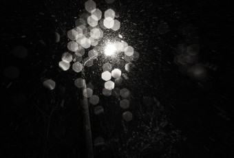 A black and white abstract photograph of a street light with falling snow. Shot with plentiful bokeh in a film noir style. Taken by Manahawkin, NJ, photographer Greg Molyneux.