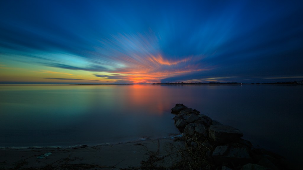A long exposure photograph taken during blue hour overlooking Barnegat Bay from a sunset park in Ship Bottom, New Jersey. A stretch of jetty rock serves as the foreground.