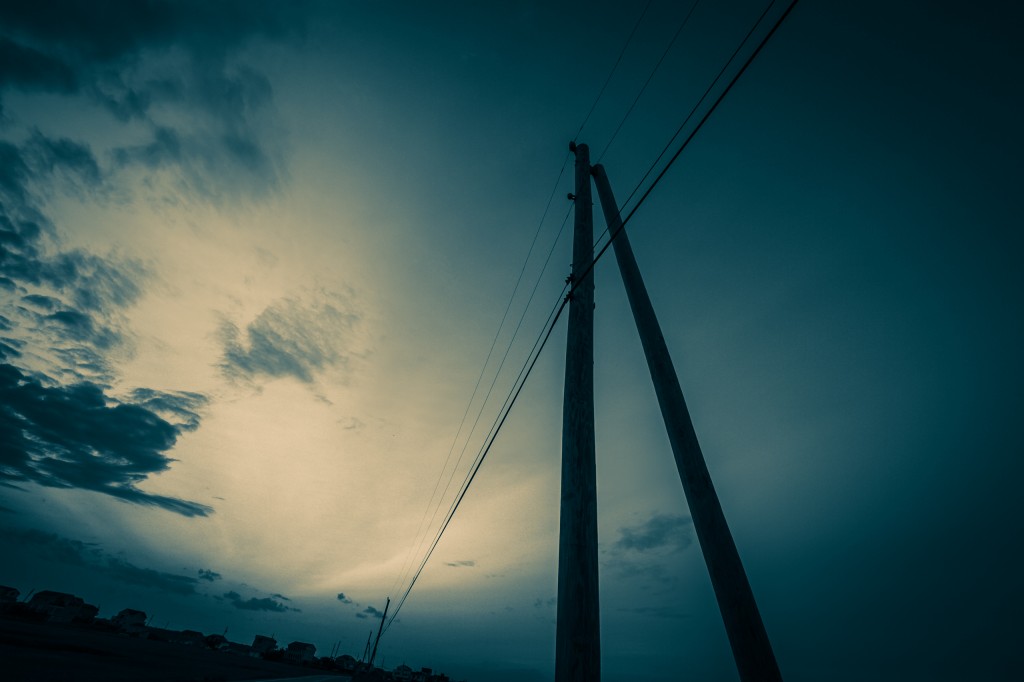 Cross processed with Trey Ratcliff's 'The Navigator' Adobe Lightroom preset, this wide angle photograph features telephone lines backdropped by a dramatic sky, all in a blue monochrome treatment.
