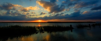 A low key HDR sunset photograph overlooking the tidal overflow of a lagoon flowing through a salt marsh.