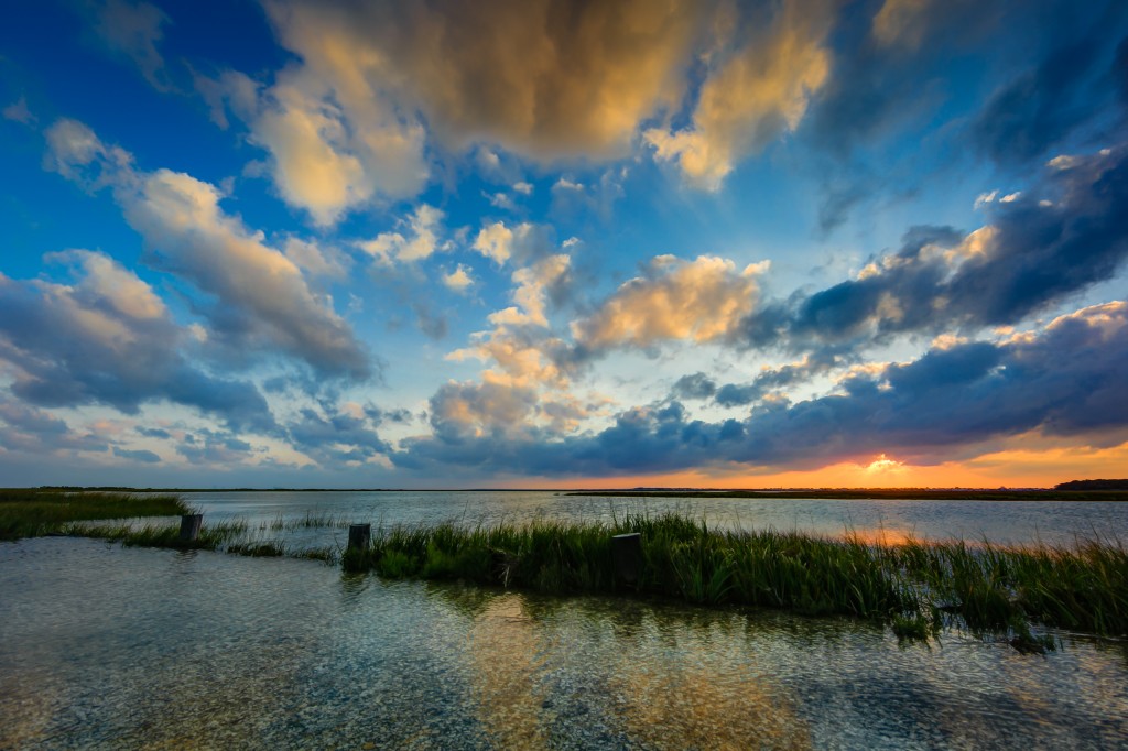 In this HDR sunset photograph, large puffy clouds illuminate the sky in the final minutes of sun.