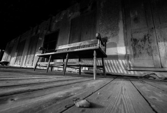 In this black and white photograph, strong leading lines move the eye through this olde tyme porch where an old wood bench sat steady for a lifetime of stories, friendship and support.