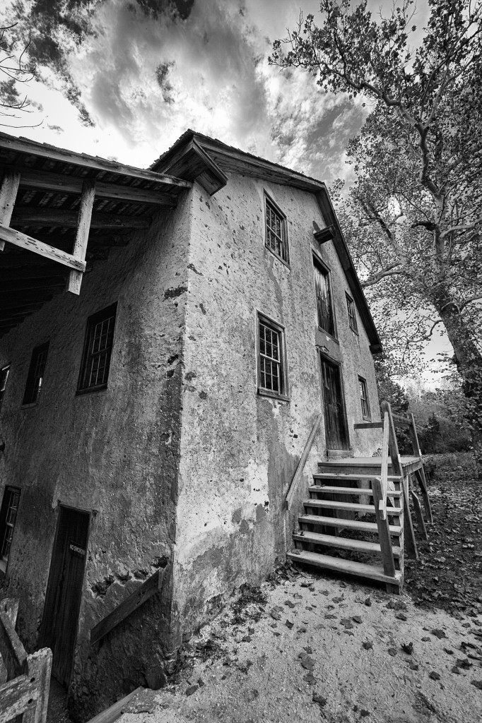 A wide angle black and white photograph of the old Batsto Village gristmill taken in portrait orientation