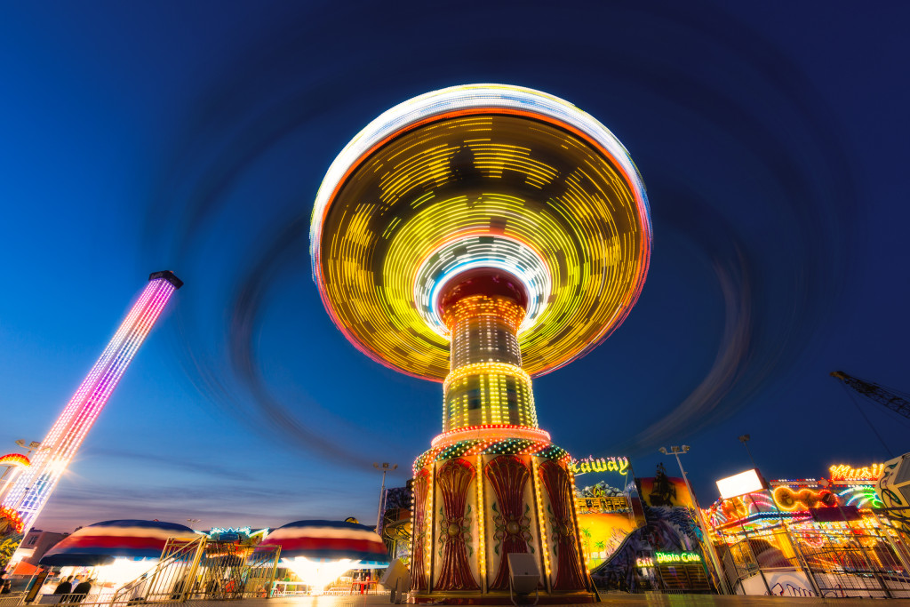 A blue hour long exposure landscape orientation wide angle photograph of Wave Swinger; a carnival swing captured in motion at Casino Pier, Seaside Heights, New Jersey.