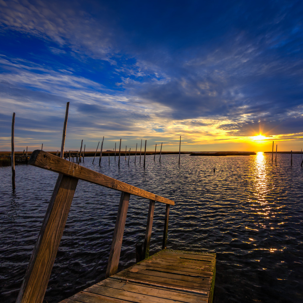 Square format HDR landscape photograph of dock and bay at sunset