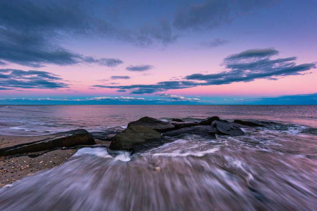 Wide angle photograph of ocean jetty rock captured at blue hour