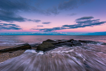 Wide angle photograph of ocean jetty rock captured at blue hour