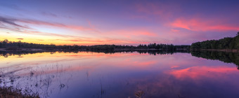 Wide angle HDR landscape photograph of a pastel color sunset over a mirrored lake at Stafford Forge