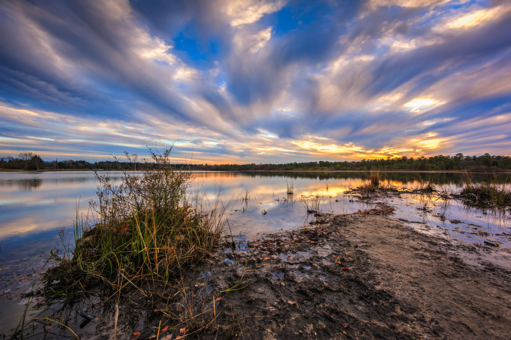 Wide angle landscape HDR photograph of wind swept clouds over still water at Stafford Forge