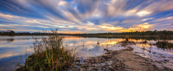 Wide angle landscape HDR photograph of wind swept clouds over still water at Stafford Forge