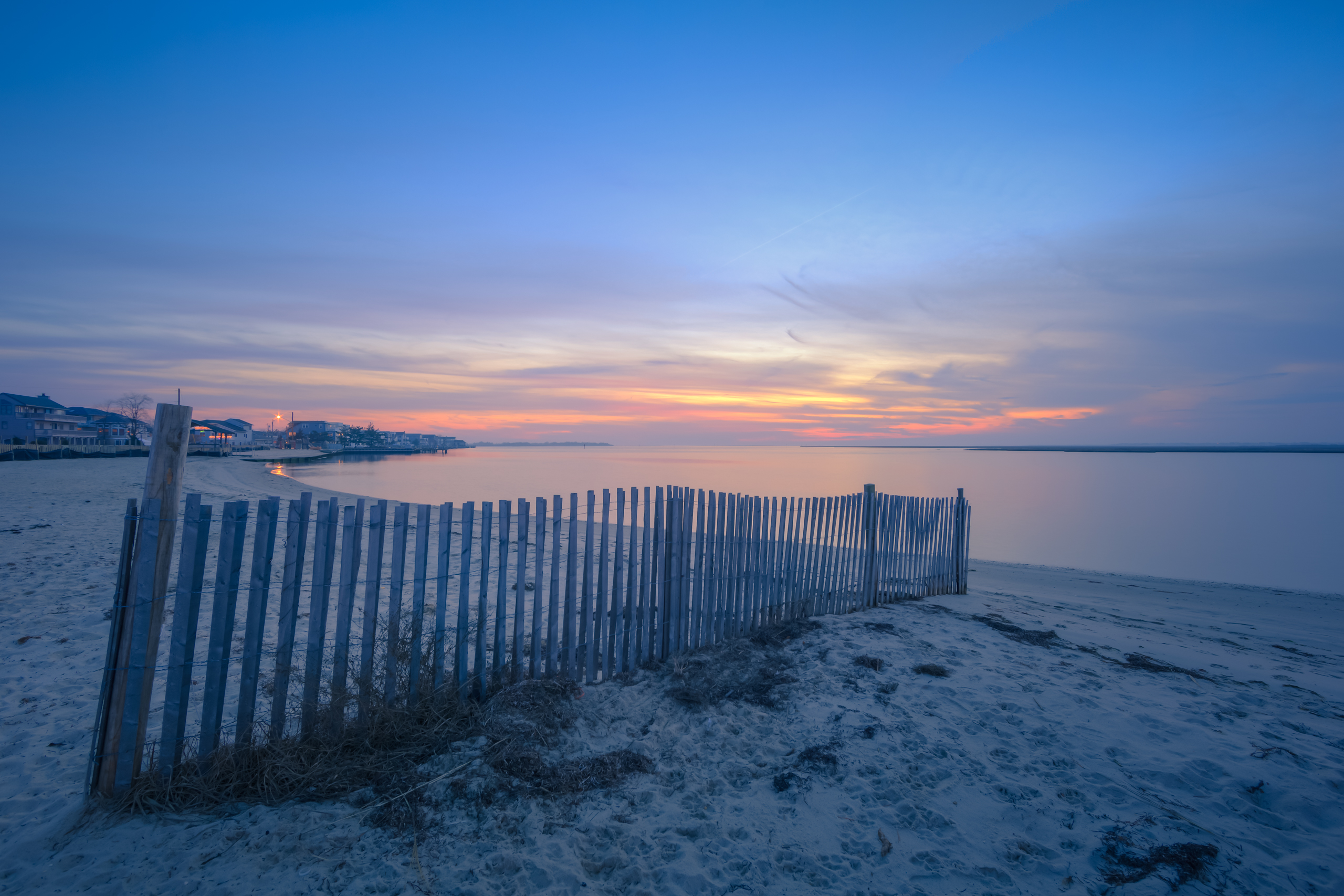 Blue hour HDR photograph overlooking dune fence and calm baywater