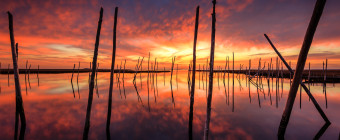 HDR photograph of a fiery sunset mirrored over reflective water