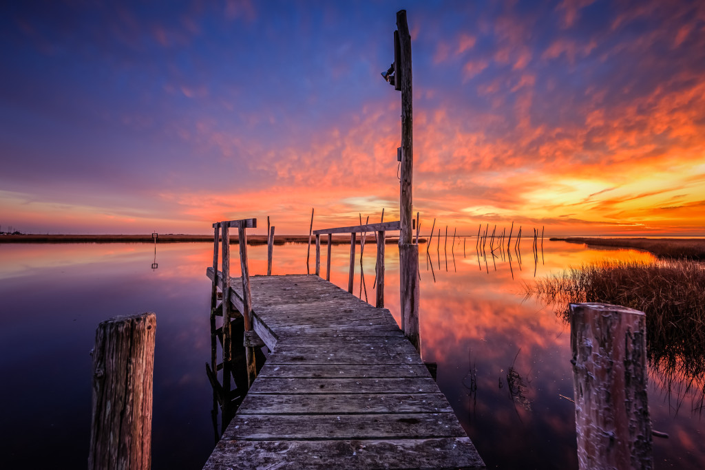 HDR photograph of an abandoned dock set afire by intense sunset color