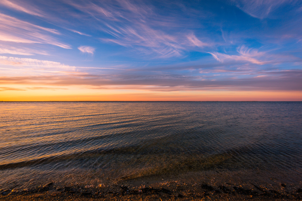 Landscape photograph of wispy clouds and a calm Barnegat Bay at sunset