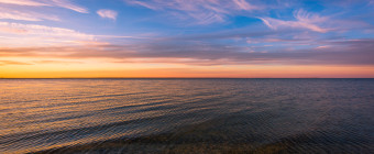 Landscape photograph of whispy clouds and a calm Barnegat Bay at sunset