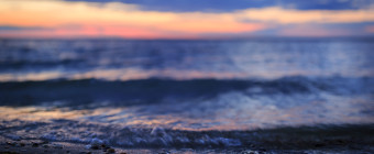 Shallow depth of field landscape sunset photo of small bay waves lapping on shore
