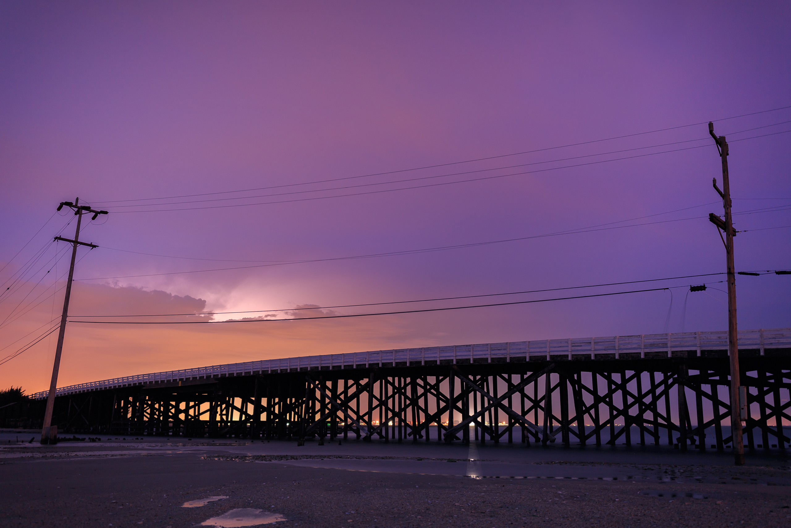 Long exposure photograph of Great Bay Boulevard's first bridge backlit by lightning.