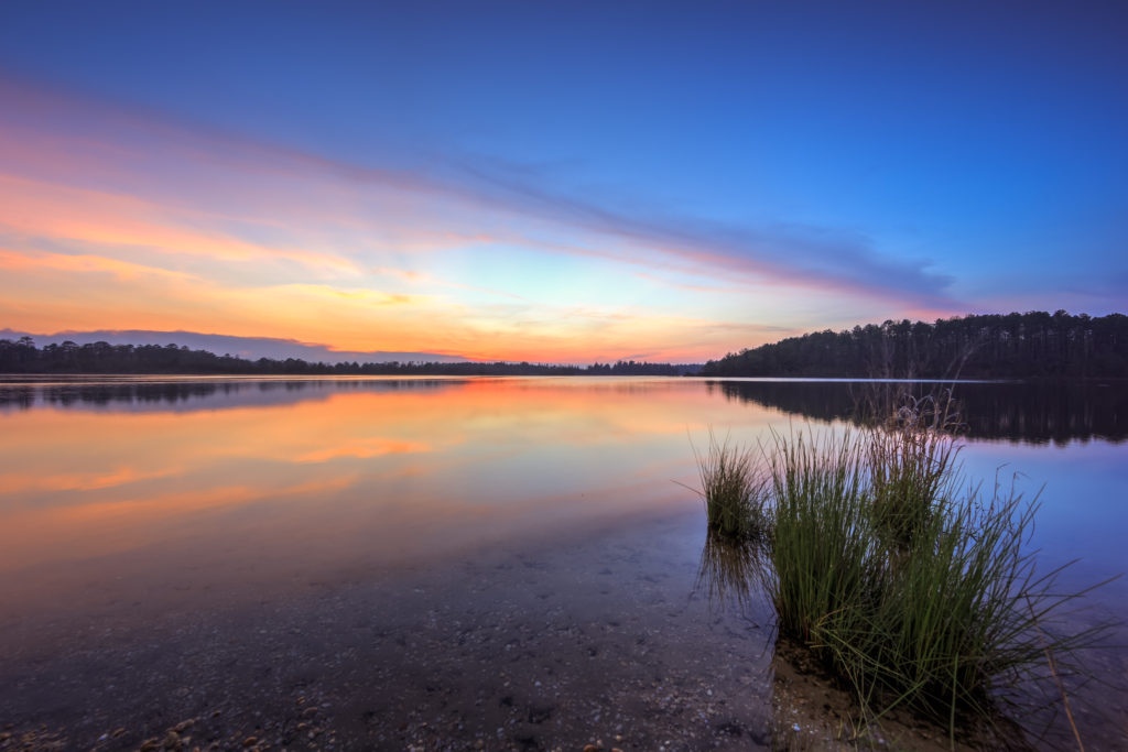 Pastel sunset photo reflected over a glassy lake at Stafford Forge Wildlife Management Area