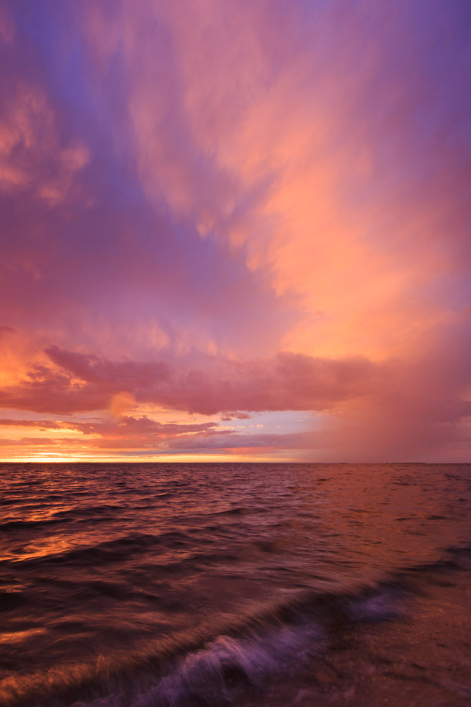 Vertical orientation sunset photograph of dramatic skies and rich pastels over Barnegat Bay.