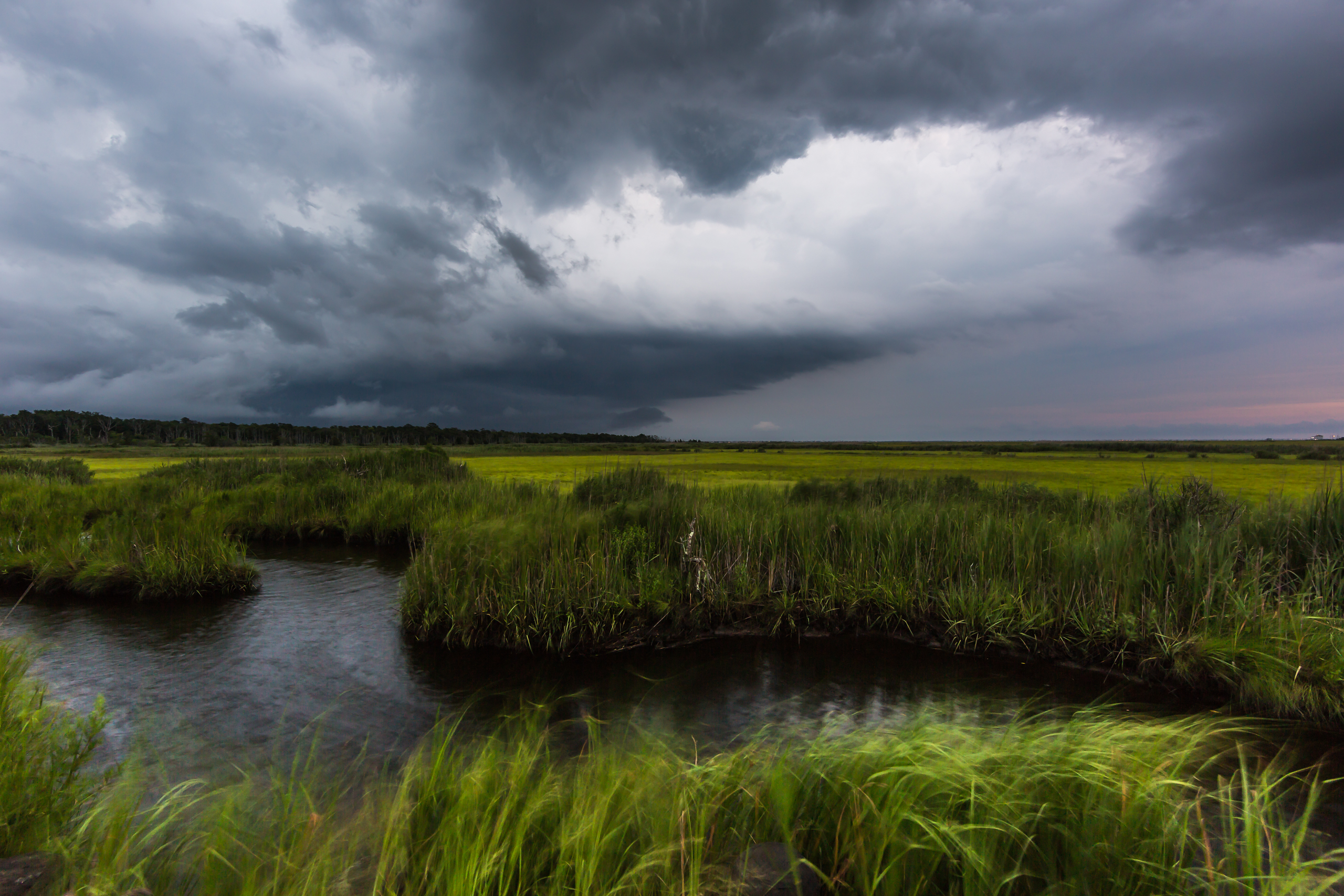 Wide angle photograph of severe weather clouds moving in over a salt marsh.