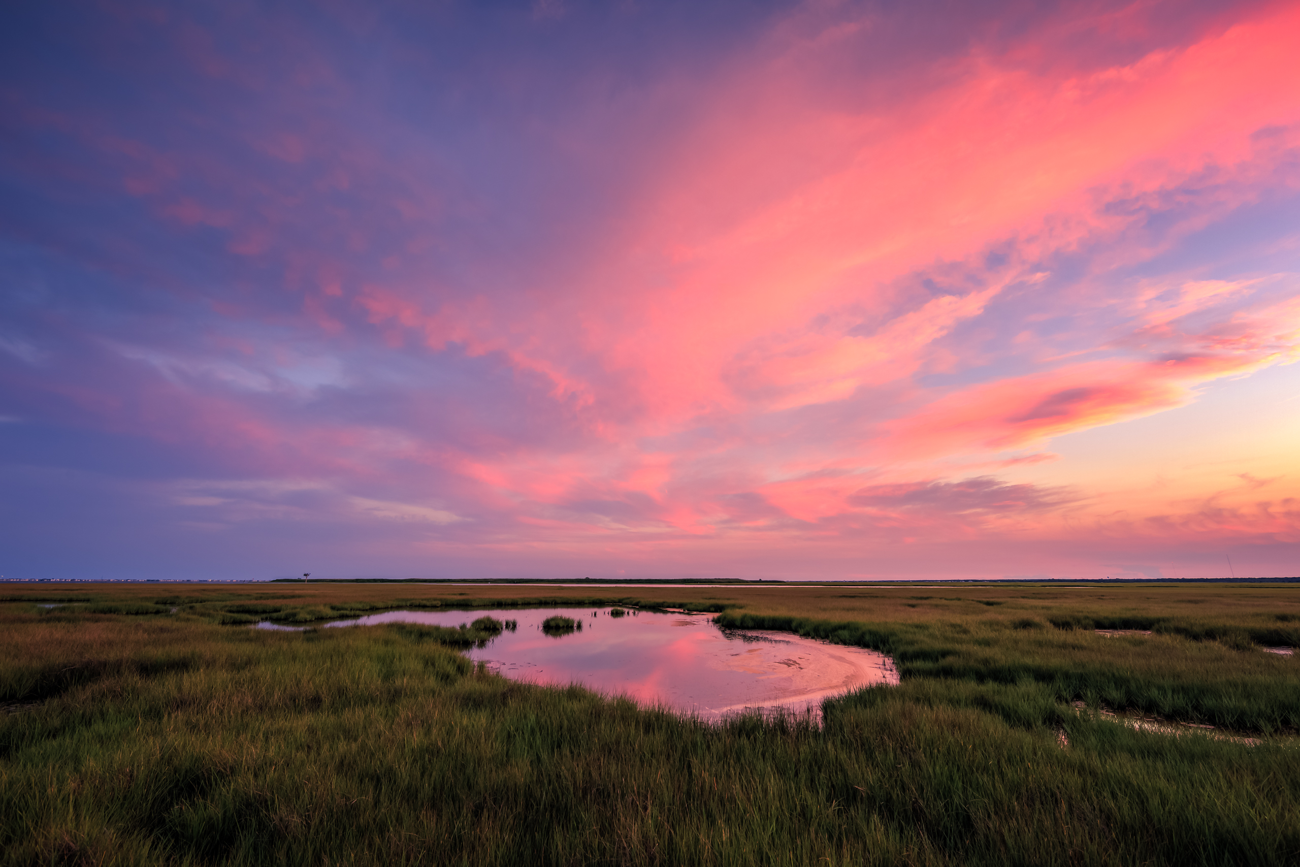 Landscape photograph of a pastel sunset sky over a summer salt marsh.
