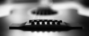 Black and white photo of acoustic guitar bridge.