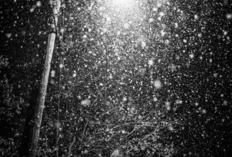Low key black and white photo of heavy snow lit by streetlight.