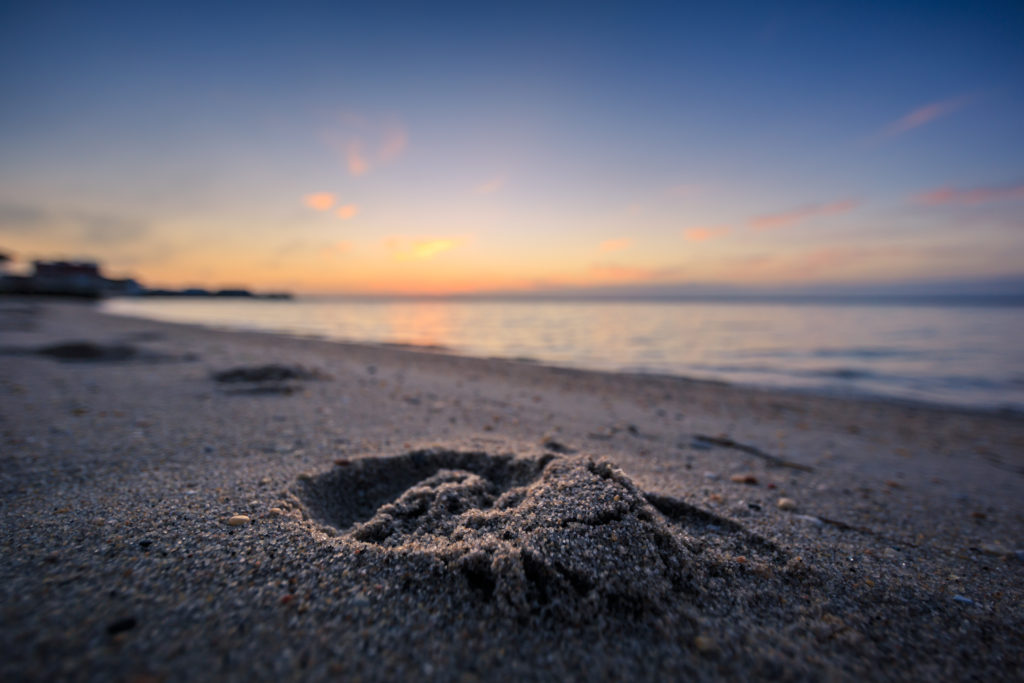 Sunset photo of a lone footprint imprinted on a bay beach.