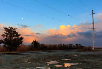 Full moon photo captured rising over pastel cumulus clouds at sunset