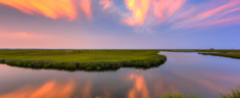 Sunset photo burns over summer salt marsh.