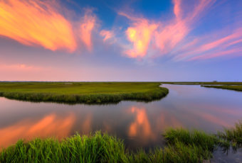 Sunset photo burns over summer salt marsh.