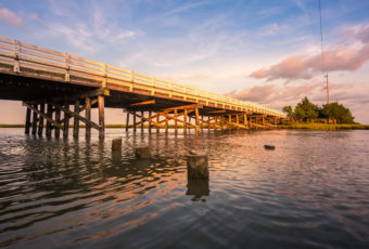 Golden hour photo of a wood bridge spanning a stretch of water.