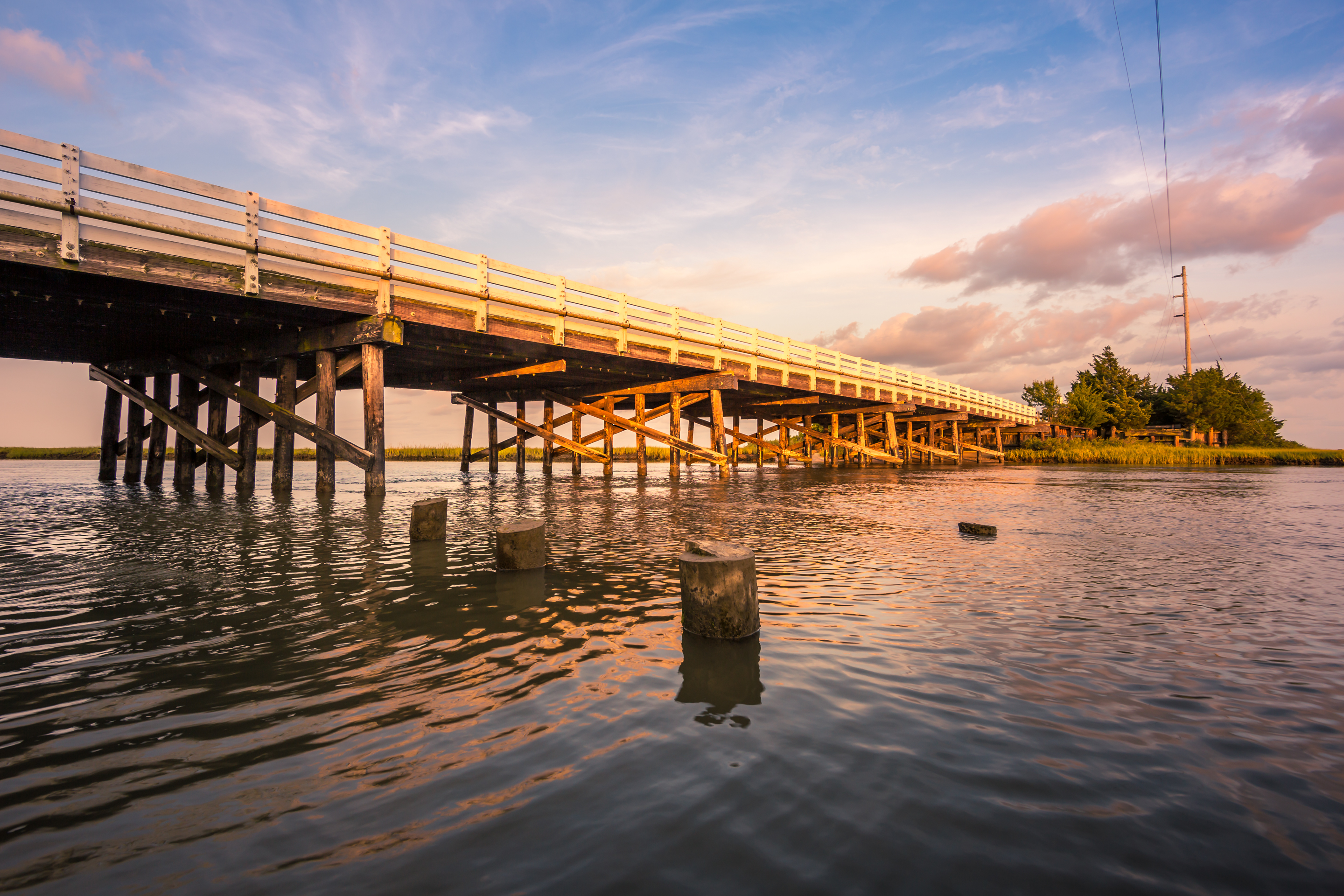 Golden hour photo of a wood bridge spanning a stretch of water.