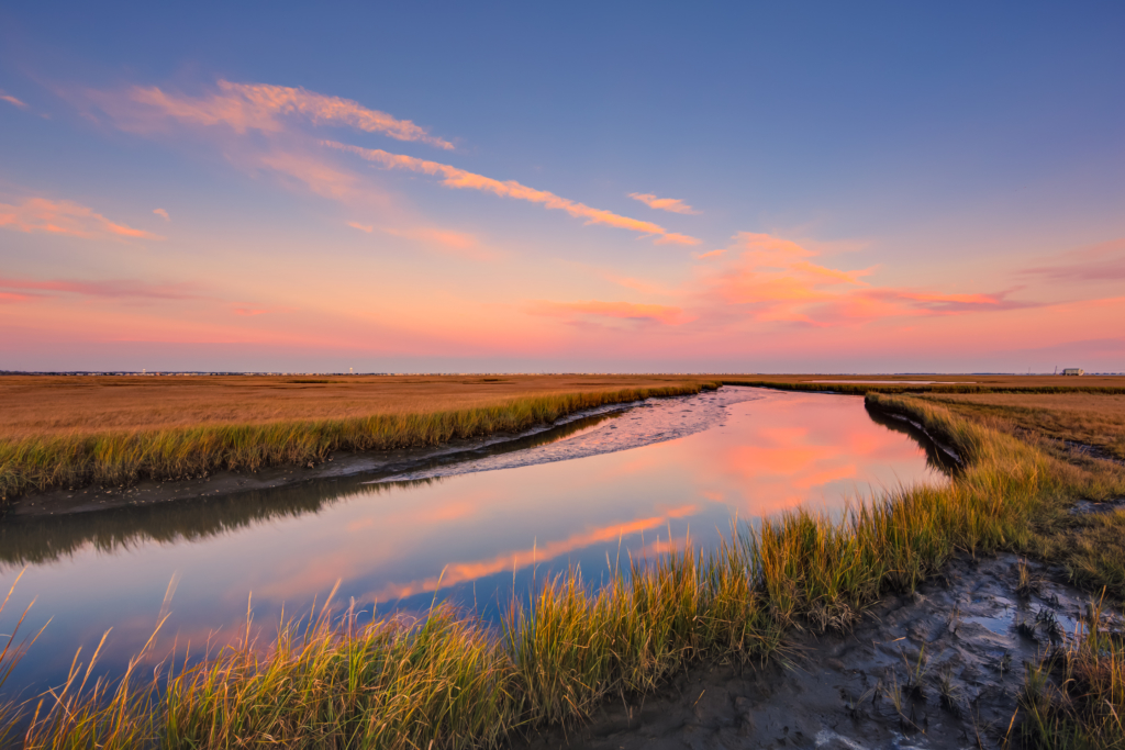 Pastel sunset over salt marsh and reflective water.