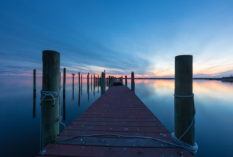 14mm blue hour photo of boat dock and calm, reflective water.