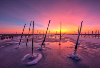 Explosive 14mm sunset photo over disused docks and frozen bay water.