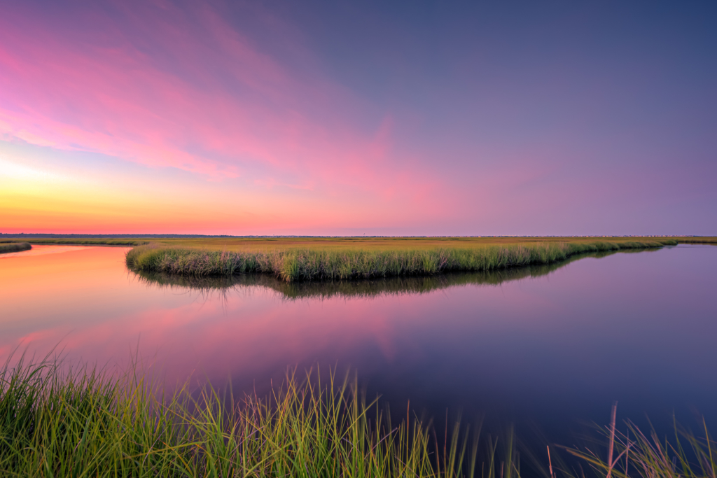 14mm wide angle sunset photo with pastel clouds and a glassy reflection on oxbow water feature at the salt marsh.