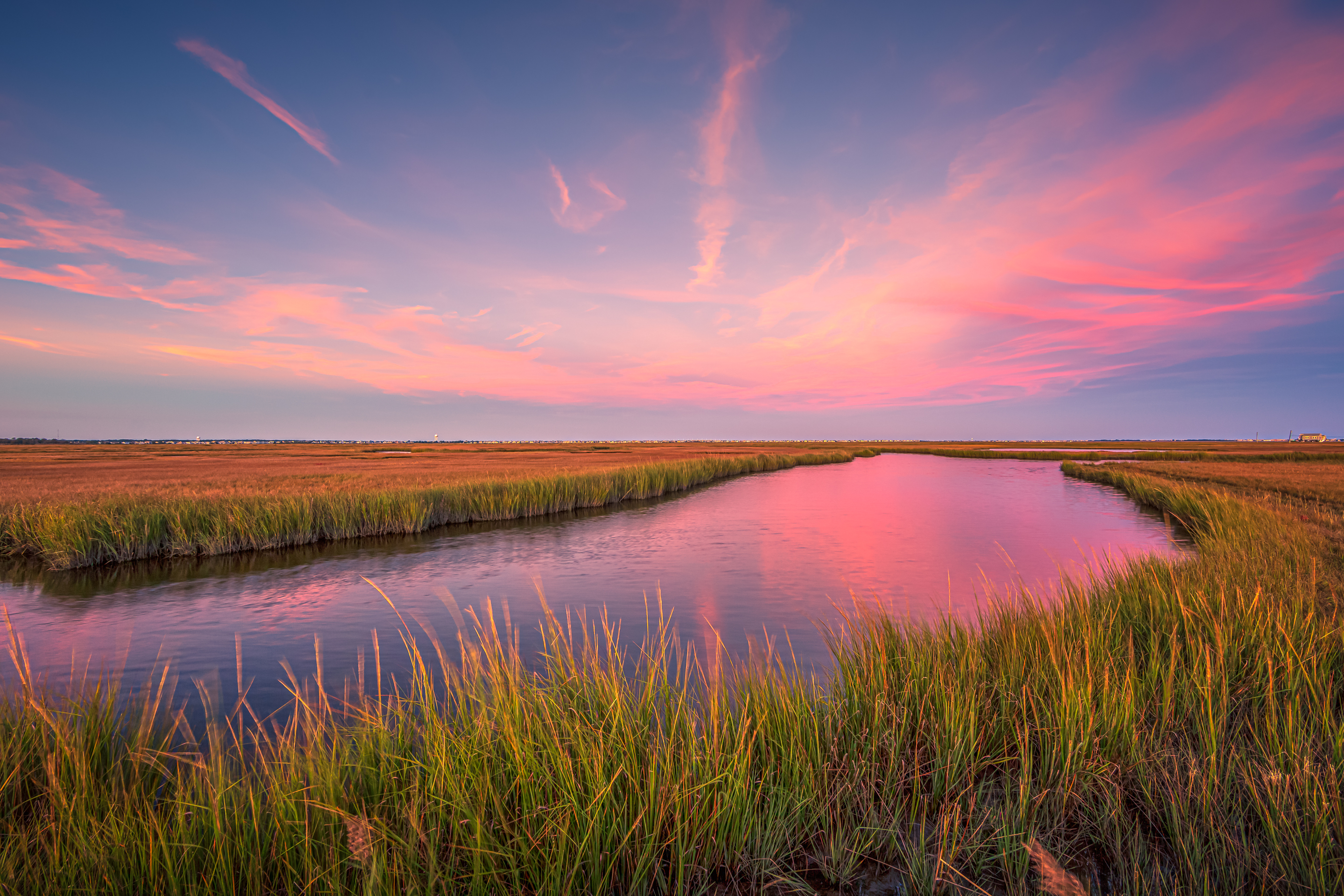 14mm wide angle sunset photo facing east over the salt marsh under pastel colored cotton candy clouds.