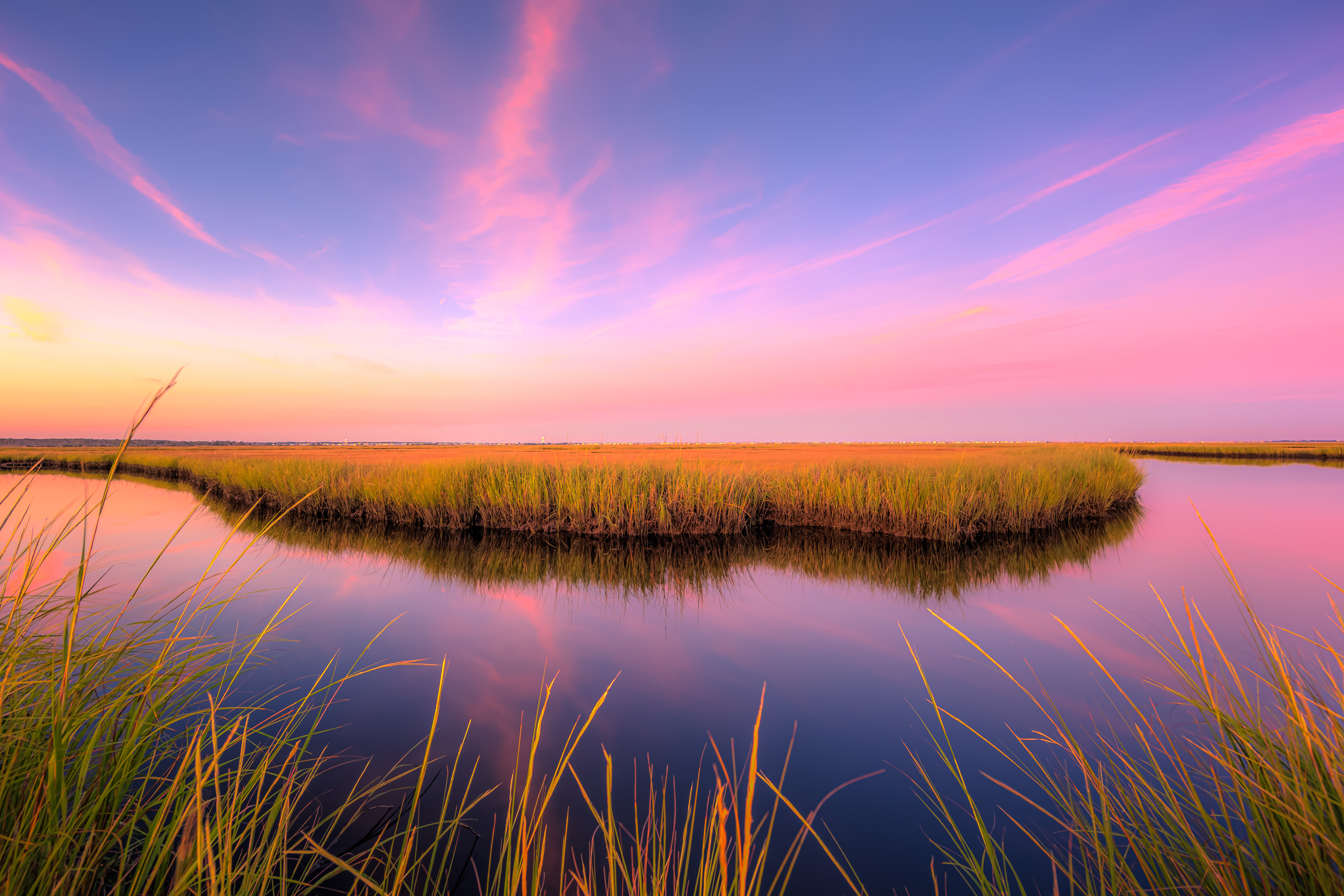 14mm wide angle sunset photo with pastel clouds, salt marsh, and calm reflective water.
