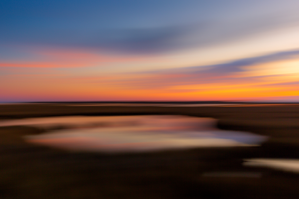 35mm sunset photo over the salt marsh using motion blur to render a brush stroke effect on the marsh and clouds. 