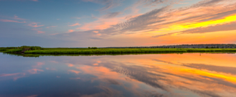 14mm wide angle sunset photograph featuring blue skies with orange, yellow, and pink pastel colored clouds reflected over mirror calm water of Cedar Run.
