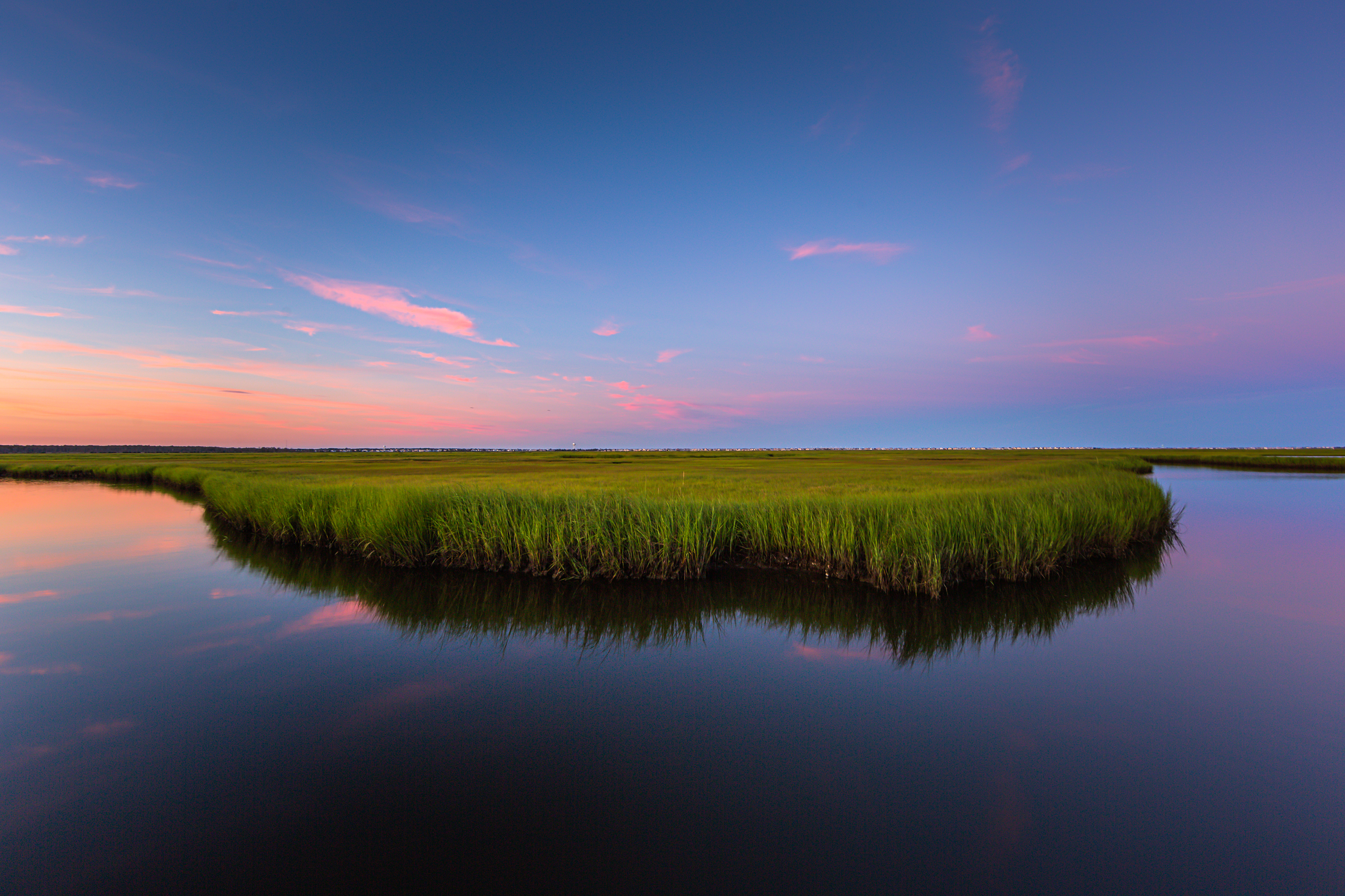 14mm wide angle photograph of a salt marsh oxbow feature at blue hour. Mirrored reflection captures the still colored pastel clouds stretched thin across the sky.