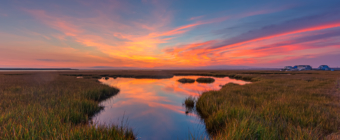 14mm wide angle photo made after sunset overlooking Cedar Run Dock Road salt marsh. Deep blues fill a sky alight with sweeping pastel clouds reflected in a marsh pool.