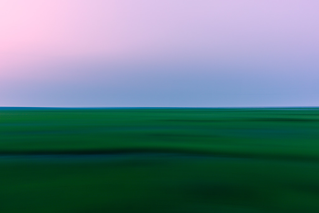 35mm photograph of green summer salt marsh at blue hour. Panning left to right creates motion blur in the landscape photograph.