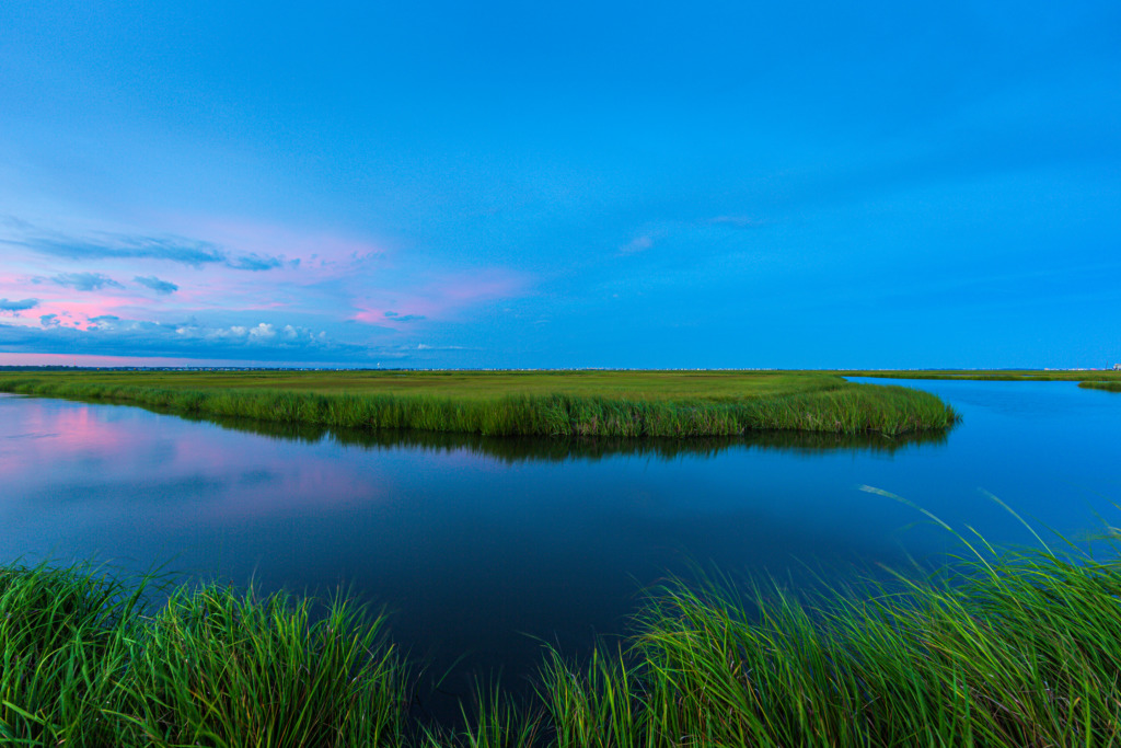 14mm wide angle photograph of an ox bow feature on Cedar Run Dock Road's salt marsh at blue hour. A hint of pink clouds twinkle in the watery reflection.
