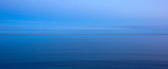 35mm blue hour photograph with the bay in the foreground and a razor thin strip of Long Beach Island in the background. Panning and a slow shudder brings motion blur into the peaceful, minimalist image.