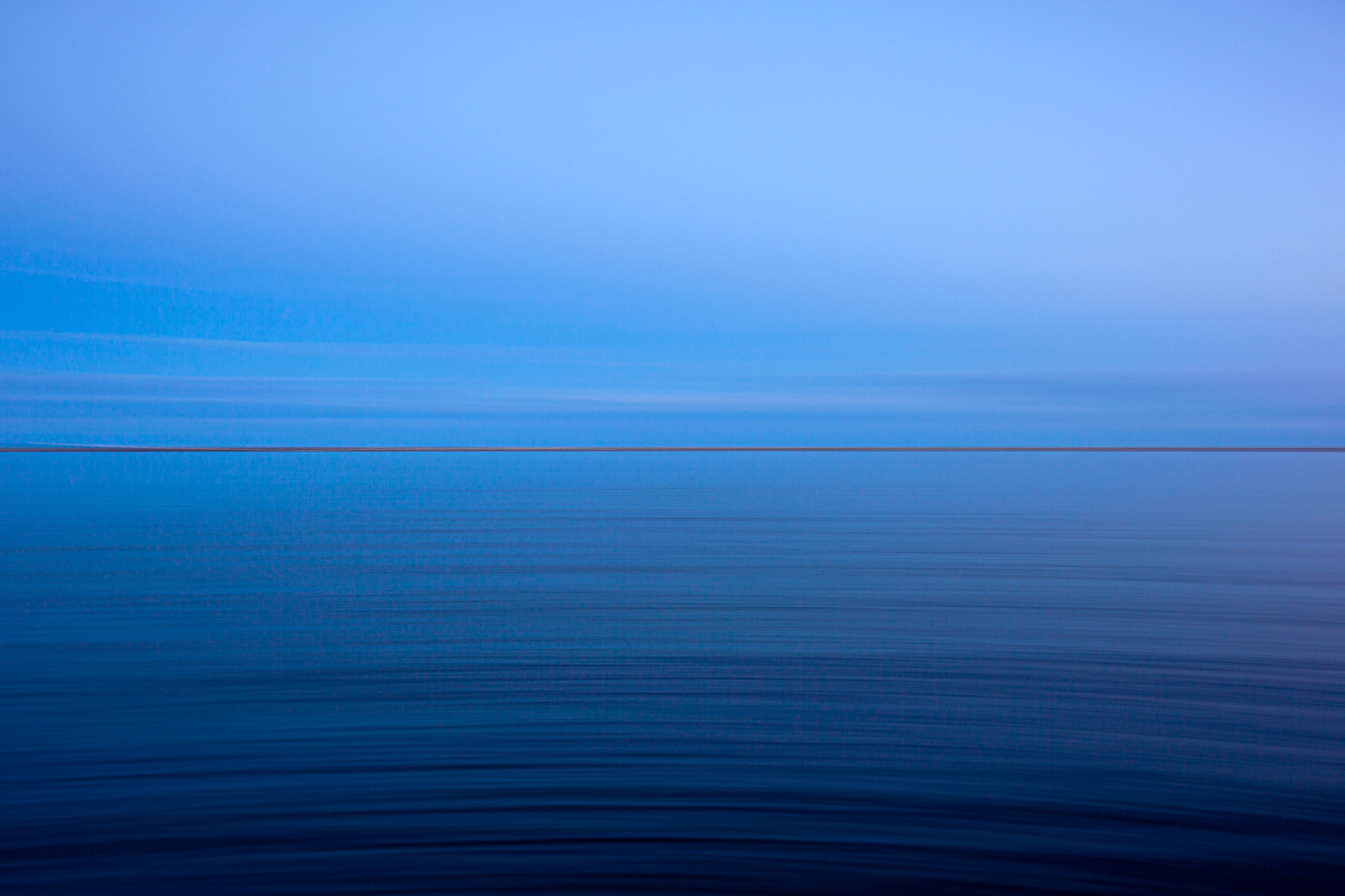 35mm blue hour photograph with the bay in the foreground and a razor thin strip of Long Beach Island in the background. Panning and a slow shudder brings motion blur into the peaceful, minimalist image.