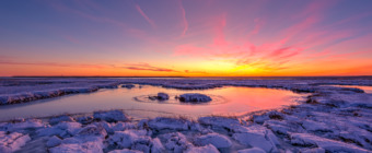 14mm winter salt marsh photograph at blue hour. Snow and ice dominate the dormant marsh grasses and tide pools as restorative pastels of pink, blue, and purple paint the whole scene.
