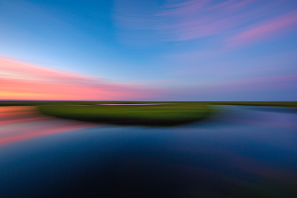 14mm sunset photo at Cedar Run Dock Road's lush green salt marsh. Left to right panning introduces motion blur to the photograph rendering a dreamy, painterly effect to the image.